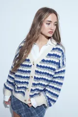 Cardigan de tejido de punto con diseño de rayas horizontales en tonos azul, gris y crema. Presenta escote en V, cierre frontal con botones grandes y mangas largas con puños anchos acanalados.