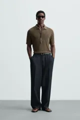 Polo negro de manga corta con cuello solapa y abertura frontal. Presenta un tejido jacquard con textura geométrica sutil.