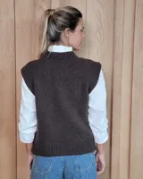 Chaleco de punto gris oscuro con diseño de trenzas y rombos en relieve, cuello redondo y terminaciones acanaladas.