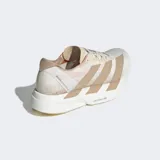 Championes de running Adidas Adizero Adios Pro 4, color blanco con detalles en beige y rosado. Presentan tres franjas laterales en color beige y mediasuela con tecnología LIGHTSTRIKE PRO.