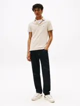 Chomba Tommy Hilfiger color beige, corte slim fit, con cuello clásico, tapeta de dos botones y logo bordado en el pecho.