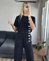Conjunto negro con pequeños lunares dorados, compuesto por una remera de mangas cortas y un pantalón palazzo con cintura elastizada.