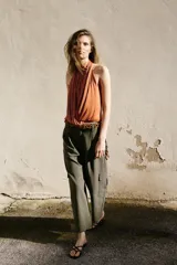 Pantalón cargo de tiro bajo color verde militar, con pinzas delanteras, pernera recta, bolsillos frontales y bolsillos laterales de plastrón. Cuenta con cierre frontal de cremallera y botones.