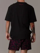 Conjunto de pijama Calvin Klein 1996, compuesto por una remera negra de algodón con cuello redondo, manga corta y logo estampado en el pecho, y un short negro de algodón tejido con bolsillos laterales, cintura elástica con logo y estampado del logo de la marca en color fucsia.