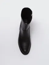 Bota corta de cuero negro con caña baja, punta redondeada y cierre lateral. Presenta un diseño minimalista y versátil.