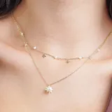 Collar doble dorado con cadena fina, dije de perla con rayos dorados y dijes colgantes de perlas y estrellas.