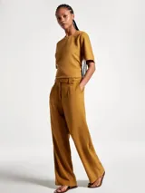 Pantalón de vestir de corte recto y tiro alto, con cierre frontal y trabillas para cinturón. Presenta pinzas en la parte delantera que aportan estructura a la prenda.