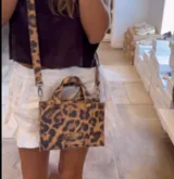 Cartera mini tipo tote bag con estampado animal print, doble asa corta y correa larga desmontable.