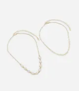 Collar de dos capas con baño dorado. La primera capa es una cadena fina con pequeños corazones ahuecados. La segunda capa es una cadena de eslabones con corazones esmaltados en blanco. Confeccionado en metal reciclado.