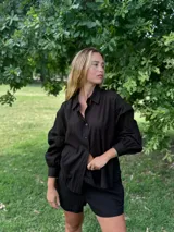 Conjunto de dos piezas compuesto por una camisa de mangas largas abullonadas con puños y cierre frontal de botones, y un short de tiro medio. Ambas prendas presentan una textura arrugada.