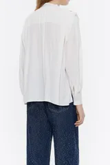 Blusa estampada con cuello con abertura a modo de cierre, manga larga con volumen y puño con botones. Maxipliegues en los hombros.