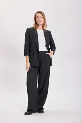 Blazer negro de corte sastrero con mangas tres cuartos, solapas clásicas y cierre frontal con un botón. Presenta bolsillos laterales con solapa.