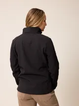 Campera softshell blanca con cierre frontal completo, cuello alto y bolsillos laterales. Presenta un bolsillo vertical con cierre en el pecho y el logo de la marca bordado.