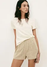 Pijama compuesto por una remera de algodón color crema con estampa pequeña en el pecho y un short de tela liviana color beige con estampado de cuadrícula fina.