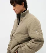 Campera bomber masculina de poliamida, con cuello, puños y ruedo de tejido elástico. Presenta cierre frontal con cremallera, dos bolsillos laterales con solapa y botón, y un pequeño bolsillo con cierre en una de las mangas.