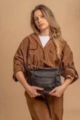 Bandolera de diseño práctico con combinación de texturas en tonos tierra, confeccionada en tela y símil cuero. Cuenta con un compartimento principal con cierre, un bolsillo frontal con cierre y correa ajustable para llevar al hombro o cruzada.