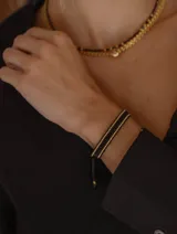 Pulsera tejida con cuentas Miyuki originales en tonos negro y dorado, con terminación de dos cuentas en acero dorado.