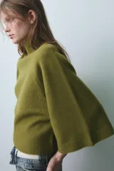Jersey de punto color verde oliva, con cuello subido y mangas anchas tipo acampanadas.