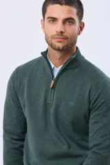 Buzo tejido de punto color verde oscuro, con cuello alto y cierre frontal parcial. Presenta un detalle en cuero en el tirador del cierre y un pequeño logo bordado en el pecho.