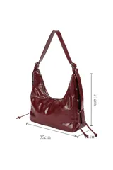 Cartera tipo hobo de material sintético con acabado brillante, diseño estructurado con laterales decorados con cordones y herrajes metálicos. Cuenta con cierre superior con cremallera y correa de hombro ajustable.