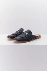 Mocasín abierto de cuero color crema con detalle de hebilla metálica plateada y flecos en el empeine.