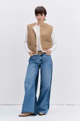 Chaleco reversible de diseño acolchado con costuras en rombos, color tostado con interior de corderito blanco. Presenta cierre frontal con botones, cuello redondo y bolsillos delanteros.