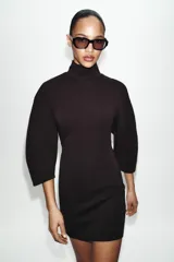 Vestido corto de tejido de punto elástico con cuello alto, manga larga y cierre posterior con cremallera.