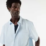 Camisa de manga corta celeste con textura seersucker, cuello camisero, cierre frontal de botones y un bolsillo aplicado en el pecho.