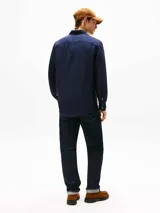 Camisa de manga larga color azul marino, confeccionada en lino pigmentado con un acabado ligeramente desgastado. Presenta cuello clásico con botones y el logo de Tommy Hilfiger bordado en el pecho.