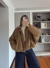 Campera tipo bomber de gamuza en color tostado, con diseño holgado, mangas amplias y cierre frontal con solapa.