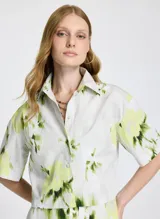 Camisa corta de mangas cortas con estampado abstracto en tonos verde y amarillo sobre fondo blanco.