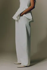 Jean blanco de denim de algodón rígido, corte baggy con tiro alto, piernas holgadas de silueta curva y diseño de cinco bolsillos.