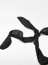 Collar con cinta de poliéster negra que se ata con un lazo y adorno central de piezas metálicas torneadas con acabado dorado.