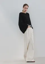 Poncho negro de diseño asimétrico, con cuello redondo y mangas amplias tipo capa.
