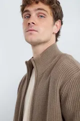 Chaqueta de punto de algodón color marrón, con cuello alto y cierre frontal con cremallera.