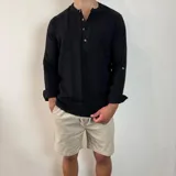Camisa de manga larga confeccionada en muselina de algodón, con cuello mao y cierre frontal de tres botones. Presenta una textura arrugada característica del tejido y puños con opción de arremangar.