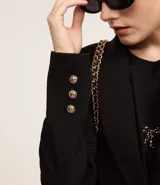 Blazer de sastrería en crepé color negro, con cuello solapa, cierre frontal de un solo botón dorado y bolsillos laterales con solapa.