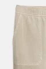Pantalón de tiro medio color amarillo, con cintura elástica, bolsillos de plastrón en el delantero y pernera holgada que se estrecha hacia el tobillo. Cuenta con cierre frontal de cremallera y botón.