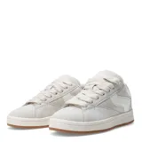 Championes de estilo urbano con diseño bicolor en negro y blanco, confeccionados en material tipo gamuza con cordones anchos blancos y suela de goma color caramelo.