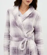 Bata de baño de corte regular confeccionada en tejido fleece suave y cálido. Presenta un diseño estampado a cuadros en tonos lila y blanco, con cuello solapa, cierre frontal mediante lazo ajustable a la cintura, mangas largas y bolsillos laterales.