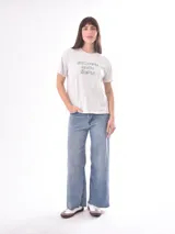 Remera de manga corta color blanco roto, con cuello redondo y estampado frontal con texto en verde.