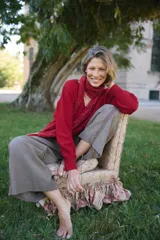 Buzo de punto color rojo, con cuello redondo, manga larga y diseño holgado. Presenta un tejido con textura en el frente y mangas.