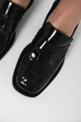 Mocasín de cuero charol negro con diseño enrejillado en la capellada y horma cuadrada.