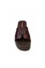 Sandalia tipo zueco Paddock de color negro, con plataforma baja de aspecto amaderado y tiras entrelazadas en el empeine. Presenta detalles de tachas metálicas doradas en los laterales y plantilla acolchada.