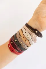 Pulsera de cuero vacuno color borgoña con broche dorado, pulsera de cuero vacuno color rosa pálido, pulsera de cuero vacuno color gris con la palabra "Guiller" grabada y pulsera de cuero vacuno color verde oscuro con la palabra "Enzo" grabada.