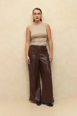 Pantalón negro de cuero sintético, corte ancho y costuras en las rodillas.