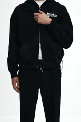 Pantalón tipo jogger negro, de corte recto y silueta clásica, confeccionado en tejido de punto de mezcla de algodón. Presenta pliegue cosido frontal, cintura elástica con cordón ajustable y bolsillos laterales y trasero insertado.