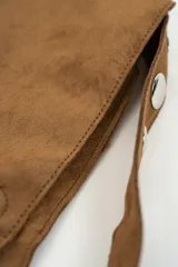 Bolso tipo baguette de gamuza color marrón, con correa ajustable mediante hebilla y cierre magnético central.