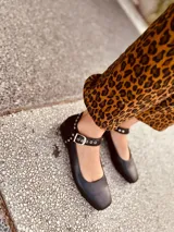 Zapato tipo Mary Jane color negro, con correa al tobillo con hebilla y detalles de tachas plateadas.