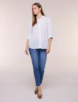 Camisa de calce holgado en género liviano con estampado a rayas verticales, cuello camisero clásico y abotonadura frontal a tono. Presenta mangas largas regulables con presilla y botón para ajustar a tres cuartos, espalda con canesú y suave pliegue central, y ruedo curvo estilo camisero.